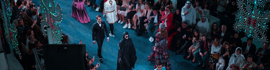 fashion runway with multiple models and a crowd