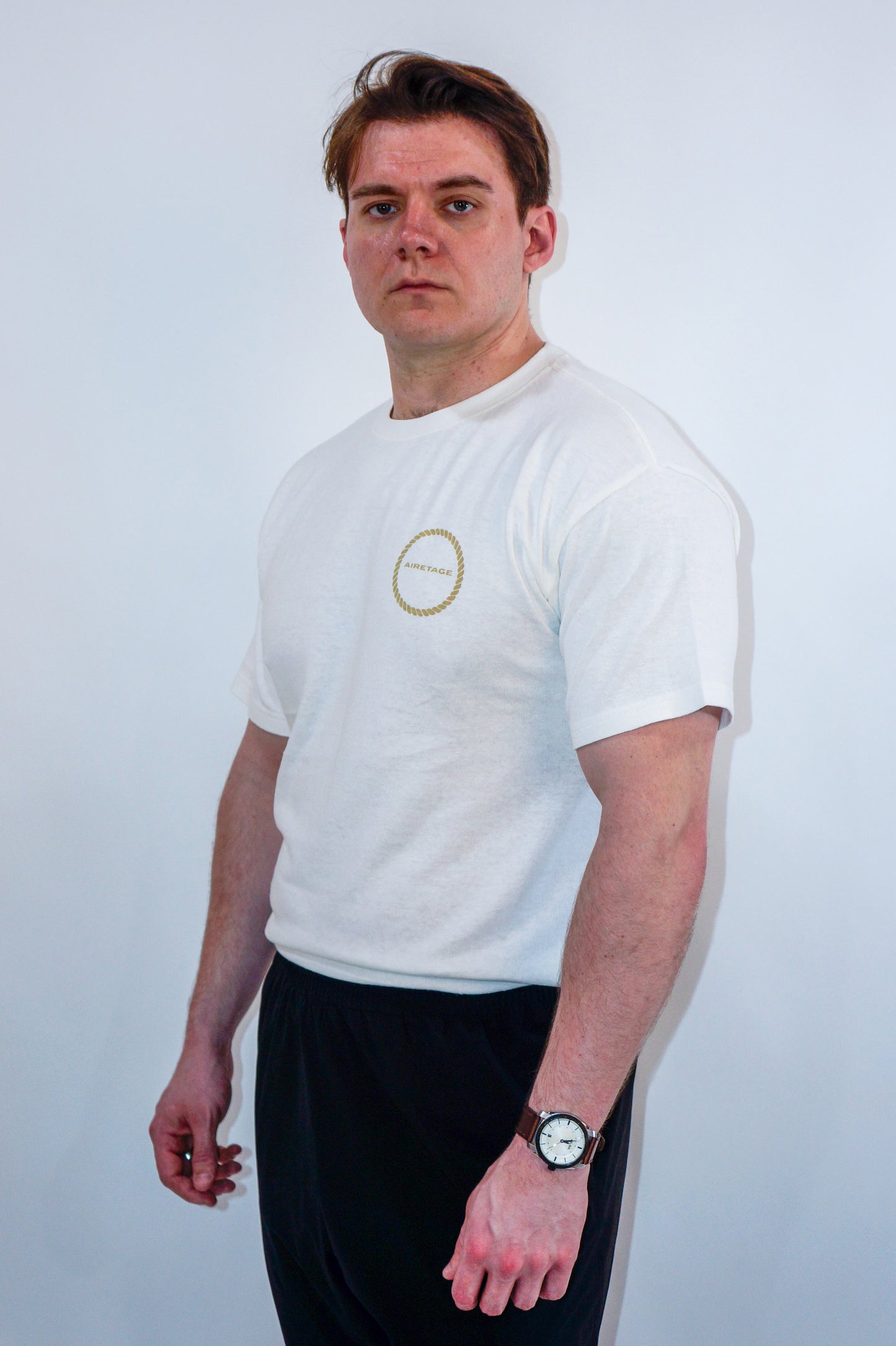 Man wearing a white t-shirt with a logo on a plain background