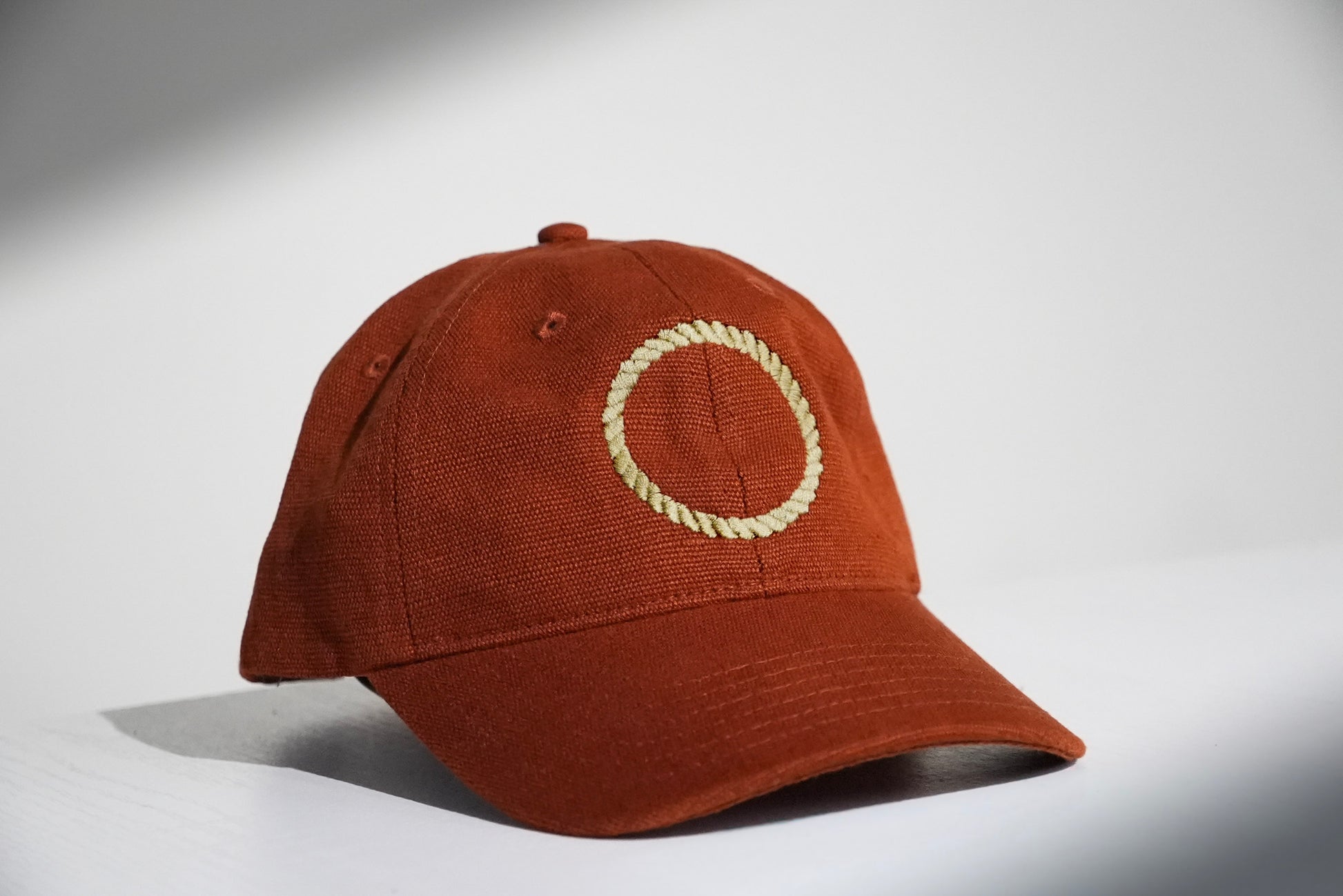 Maroon hat with embroidered circular design on grey backdrop